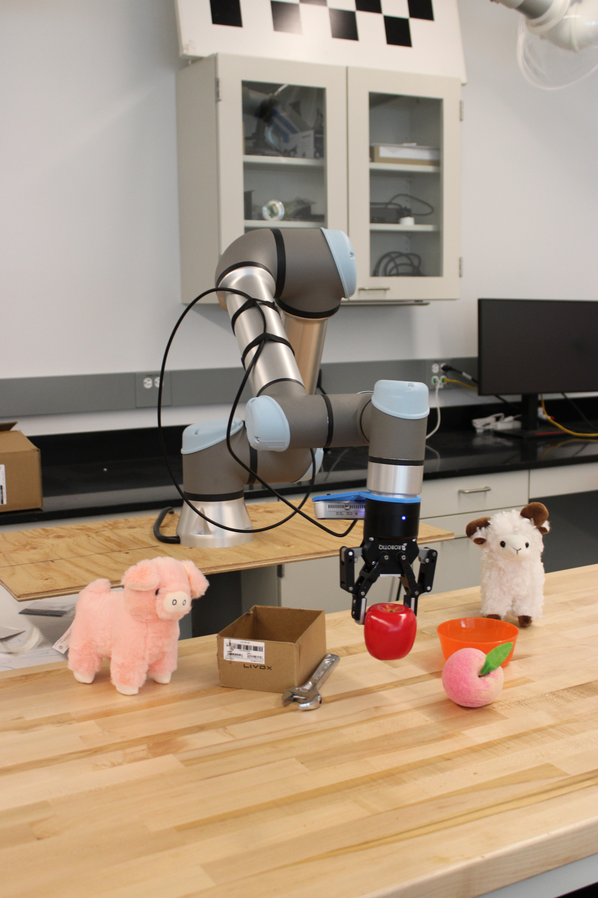 A robot arm picking an apple up from a table of toys