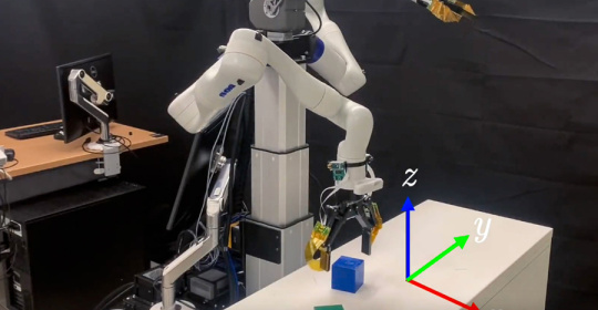 Robot arm, attached to a table, is selecting and picking up blocks.